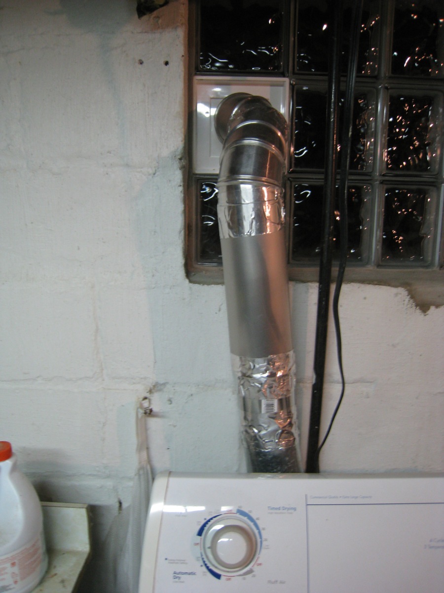 Dryer properly venting from the appliance through a glass block window with rigid vent piping.