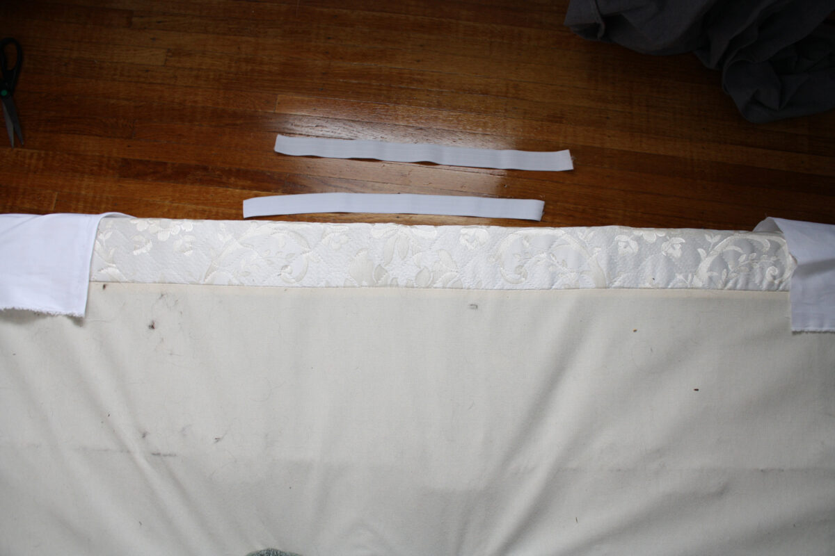 Pieces of unstretched elastic positioned behind the head of the boxspring.
