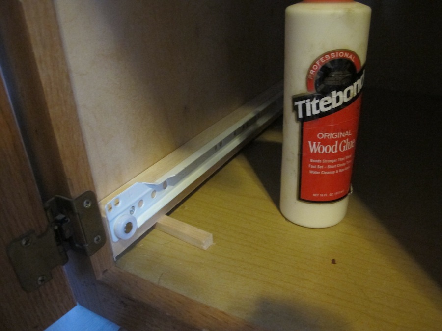 Little pieces of scrap wood shim the sliders up just enough to clear the cabinet threshold.