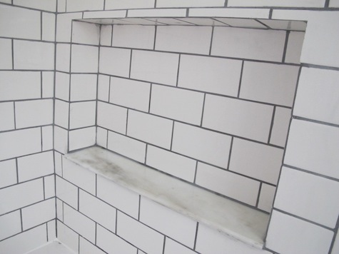 Finished white subway tile with pewter gray grout.