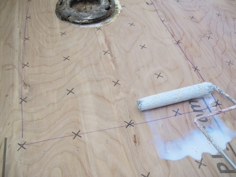 Rolling conditioner on plywood to enhance bond of vinyl tiles.