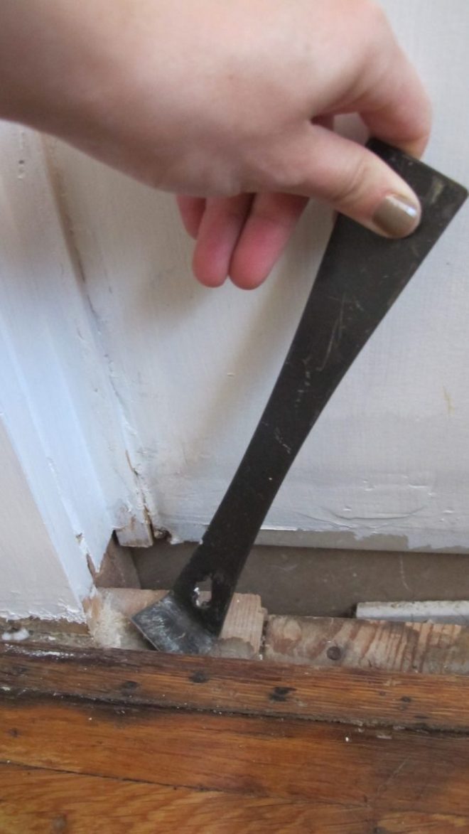 Removing the offending hardwood floorboard gently with a pry bar.