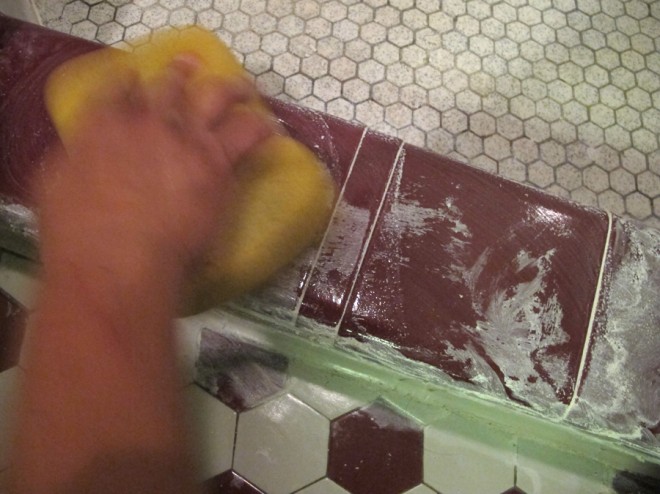 Cleaning excess grout from the shower threshold.