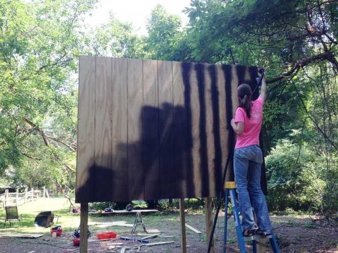 Spraying stain onto our t1-11 treehouse panels.