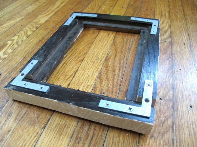 Using mending strips to reinforce a DIY picture frame weighted by stone.