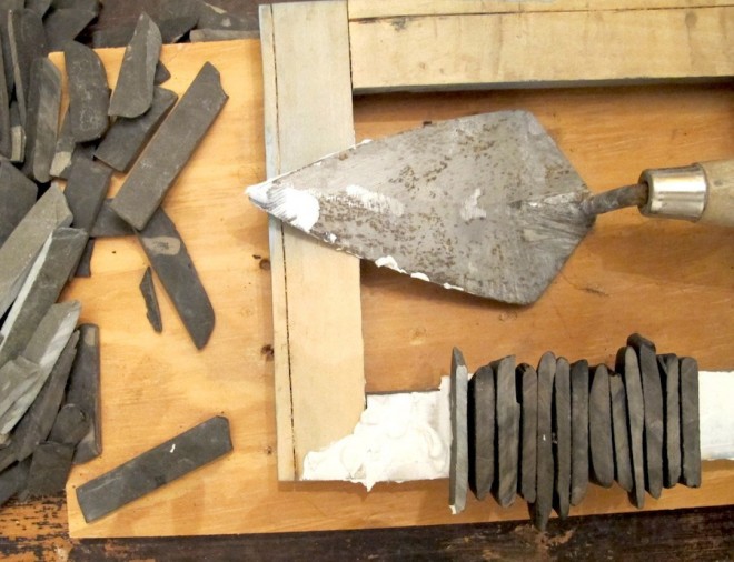 Use mortar to attach cut stones to a picture frame.