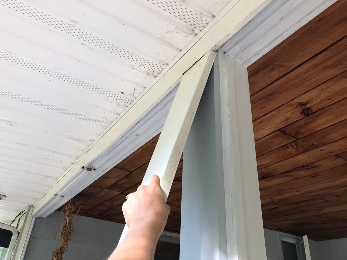 Remove vinyl trim that wrapped the wooden posts on the porch to expose the wood, and re-paint.